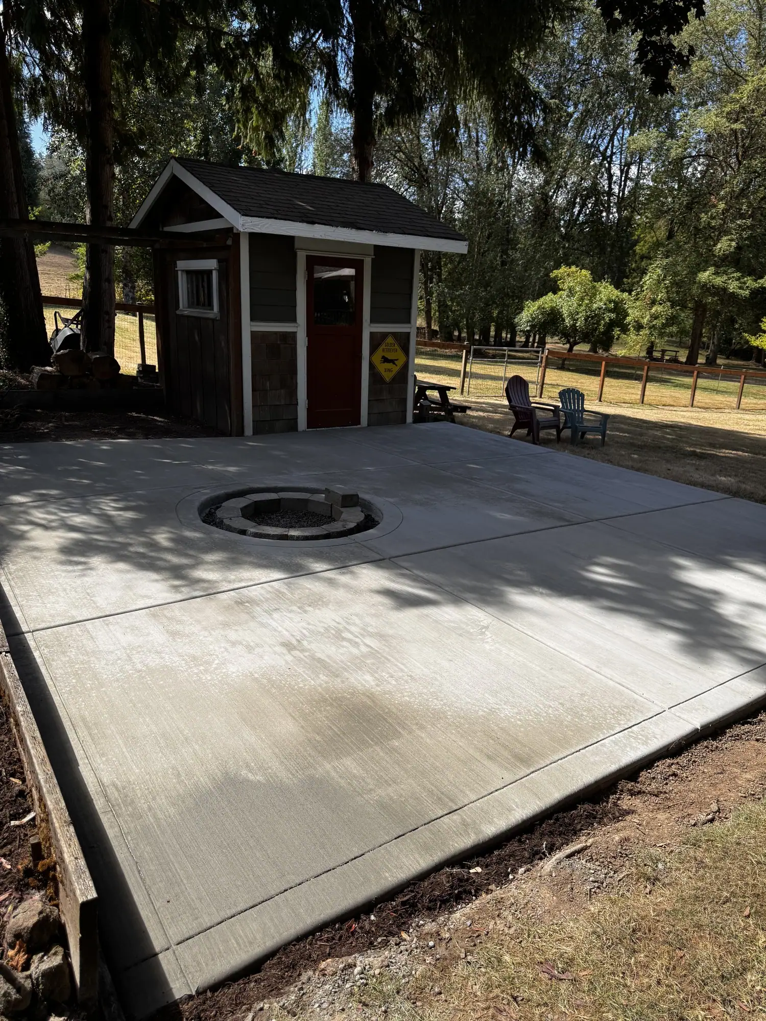 Backyard concrete patio poured in front of a garden shed