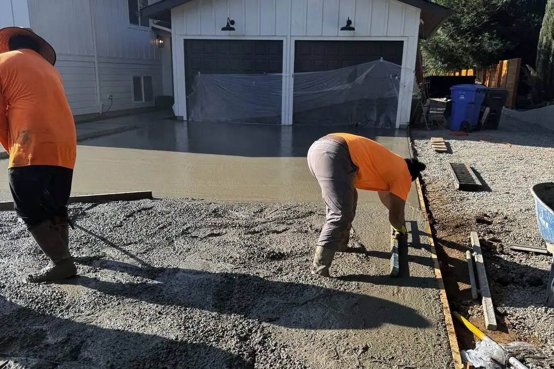 MJ Concrete crew pouring a new concrete driveway in front of a garage