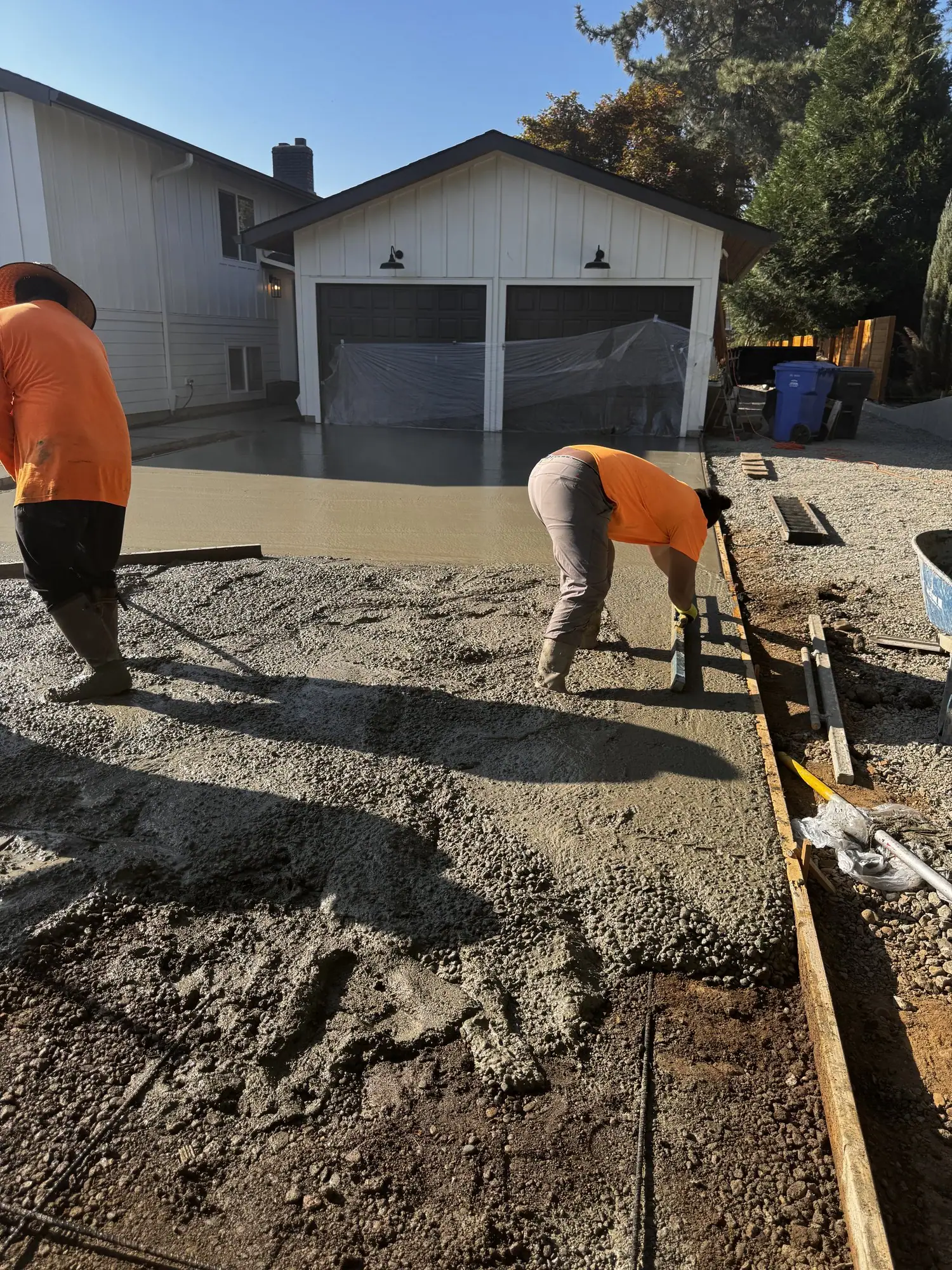 MJ Concrete crew pouring a new concrete driveway in front of a garage