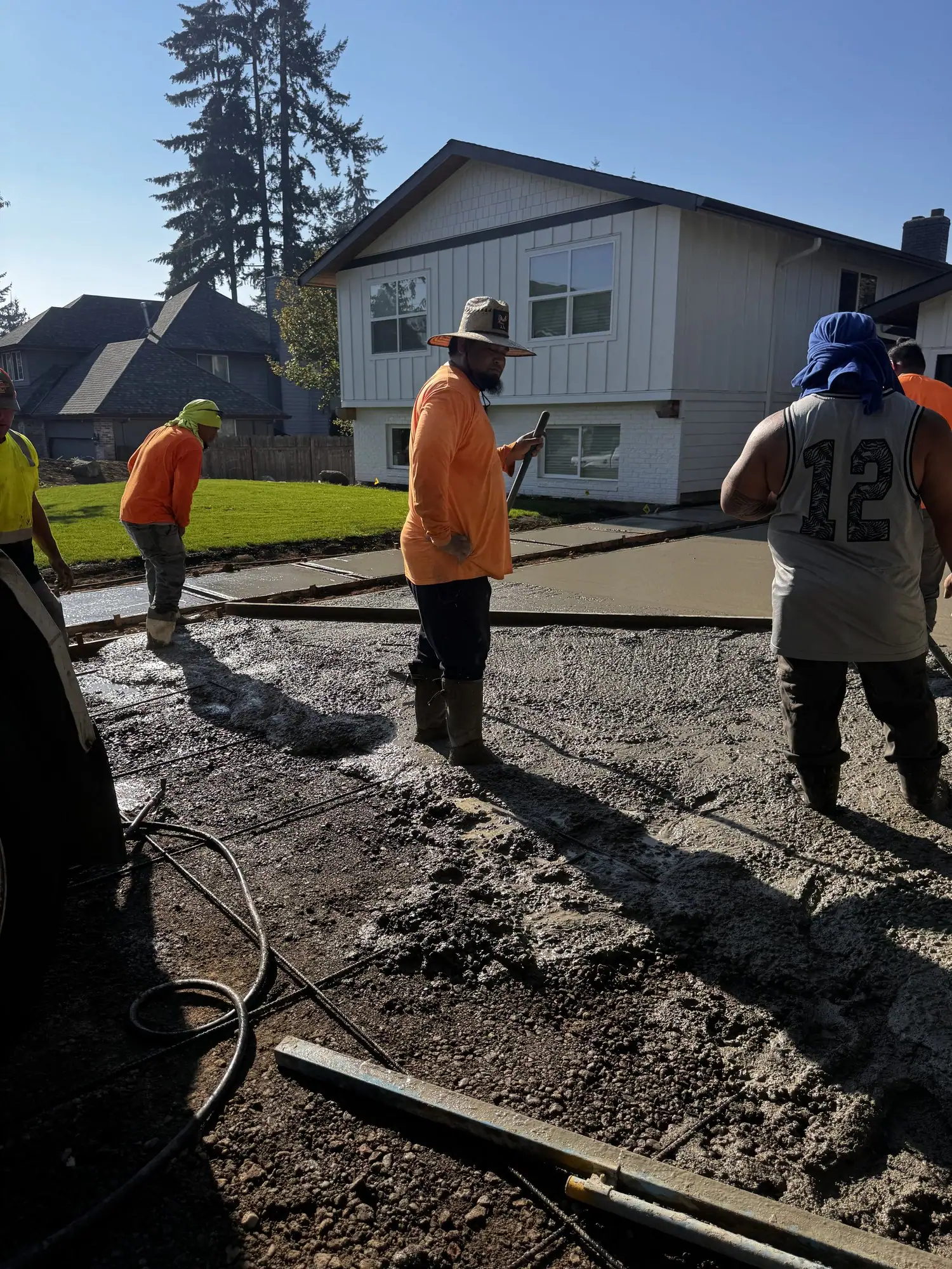 MJ Concrete crew spreading wet concrete for a driveway