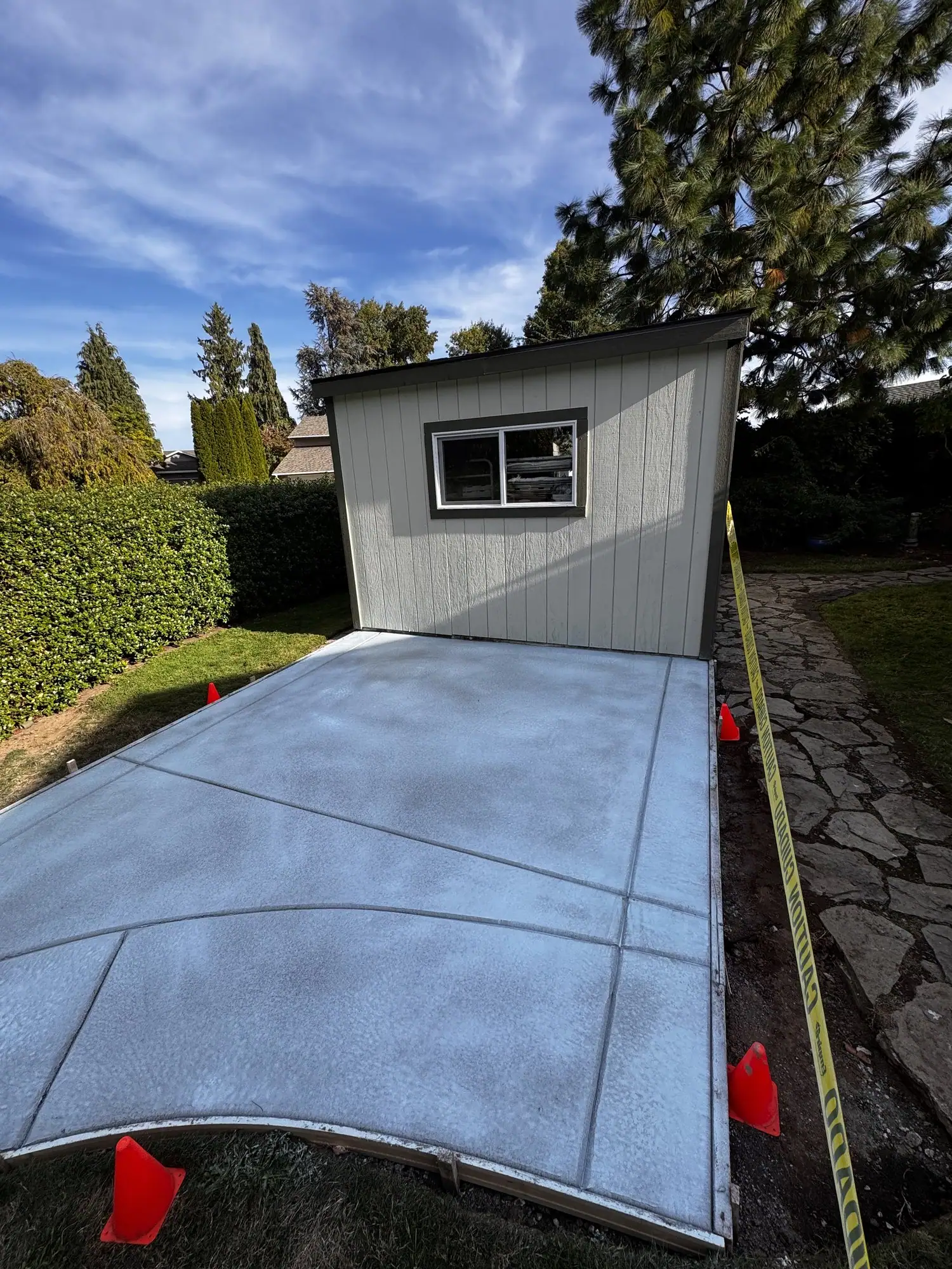 Concrete slab with a curved edge leading to a backyard shed