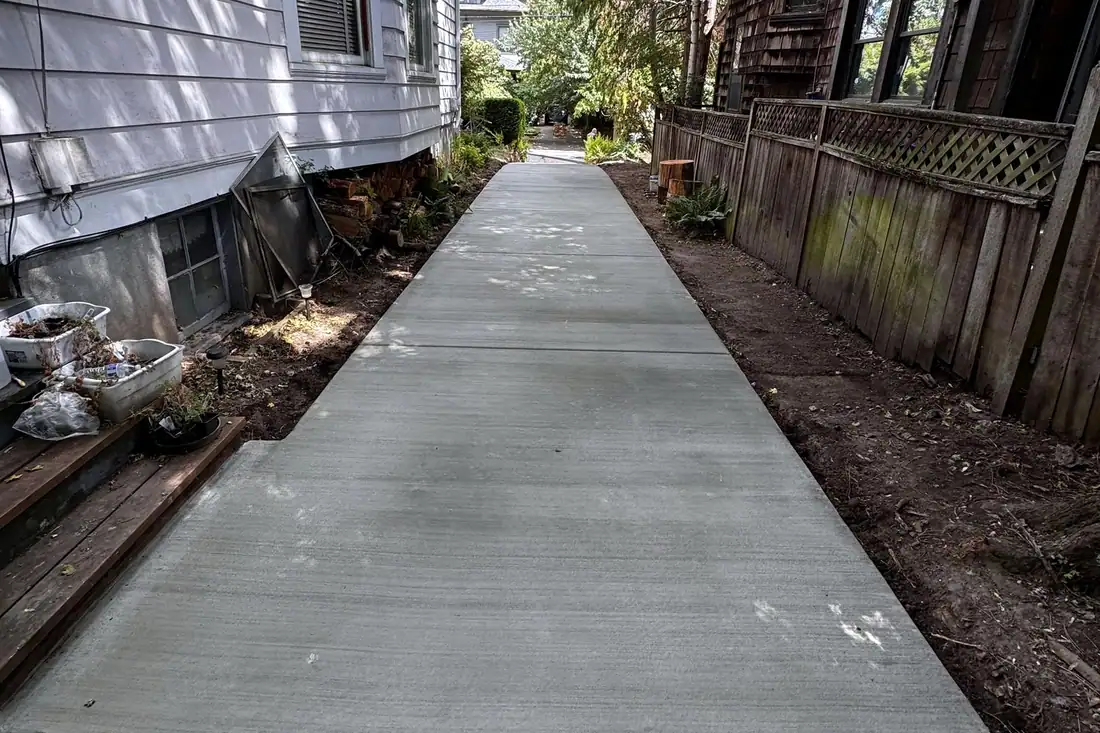Straight broom finish concrete walkway along the side of a house