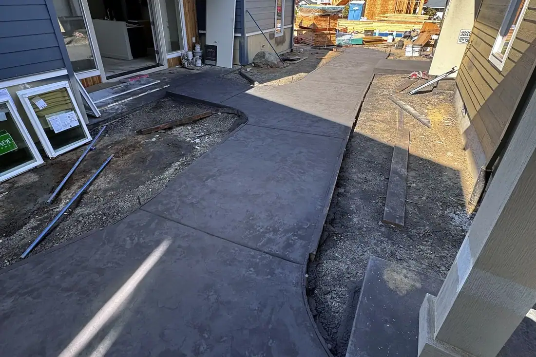 Dark gray stamped concrete patio along the back of a house